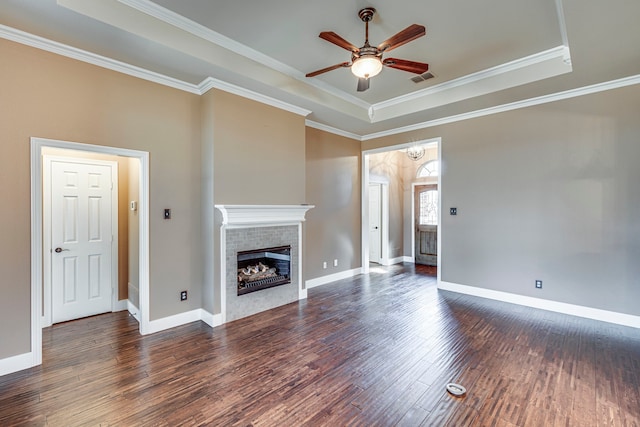 unfurnished living room featuring a fireplace, a raised ceiling, ornamental molding, dark wood-type flooring, and ceiling fan