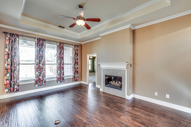 unfurnished living room featuring ceiling fan, dark hardwood / wood-style floors, ornamental molding, and a raised ceiling