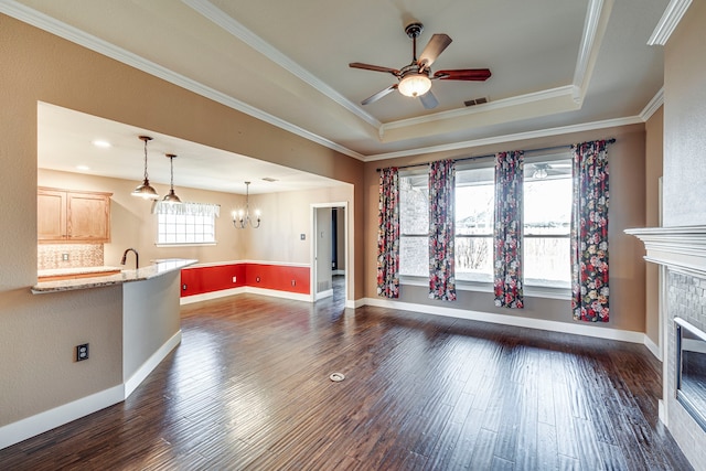 unfurnished living room featuring crown molding, plenty of natural light, and a raised ceiling