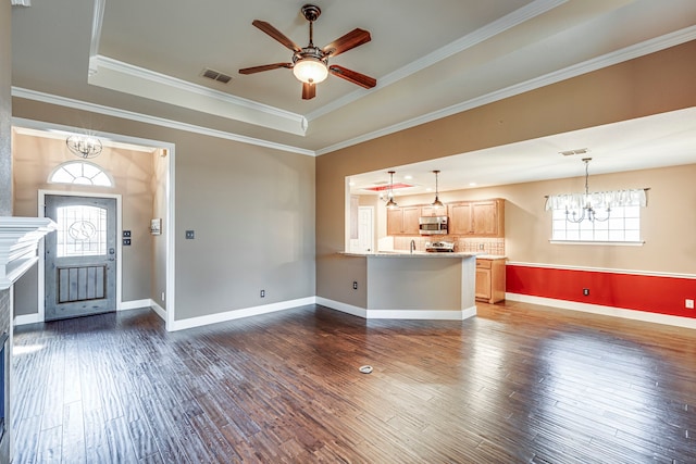 unfurnished living room with dark wood-type flooring, plenty of natural light, a raised ceiling, and ornamental molding