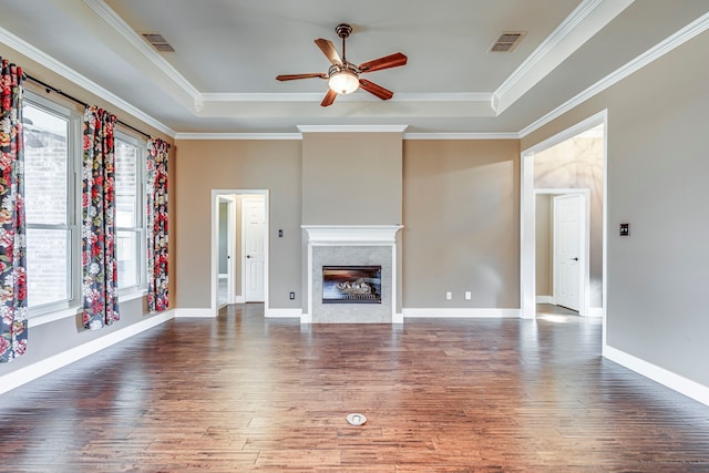 unfurnished living room with crown molding, dark hardwood / wood-style floors, a tile fireplace, and a raised ceiling