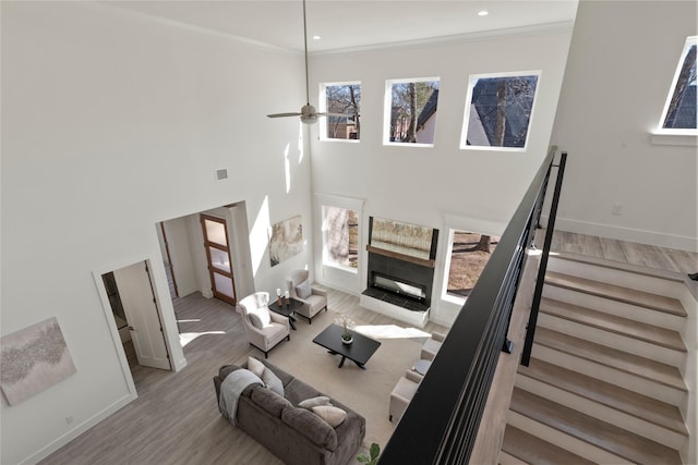 living room featuring ornamental molding, a towering ceiling, and light hardwood / wood-style floors