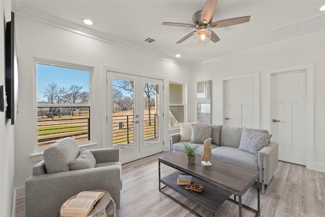 living room featuring ornamental molding, ceiling fan, and light wood-type flooring