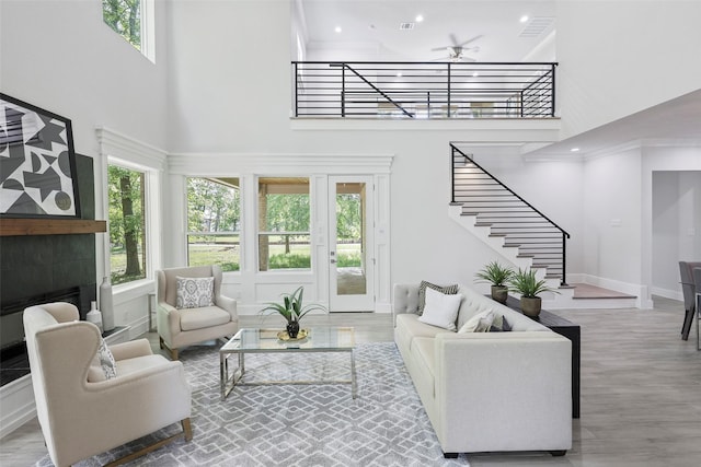 living room with wood-type flooring, a towering ceiling, ceiling fan, and ornamental molding