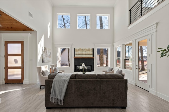 living room with a wealth of natural light, ornamental molding, and light wood-type flooring