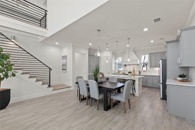 dining area with ornamental molding, sink, and light hardwood / wood-style floors