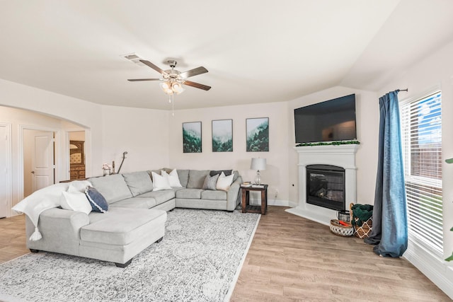 living room with light hardwood / wood-style floors, ceiling fan, and vaulted ceiling