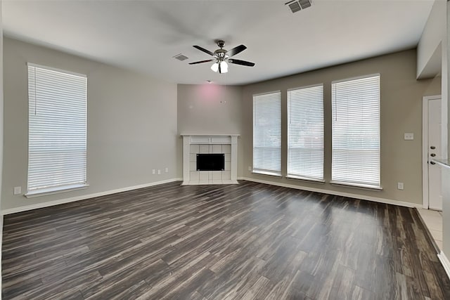 unfurnished living room featuring a wealth of natural light, dark hardwood / wood-style floors, and a tile fireplace