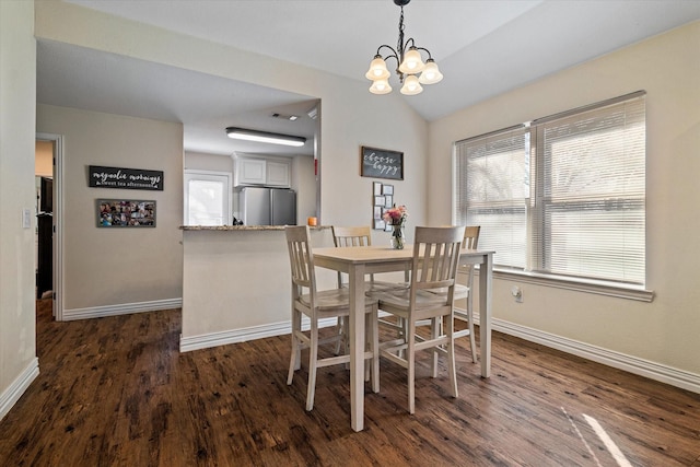 dining space featuring an inviting chandelier, dark wood-type flooring, and vaulted ceiling