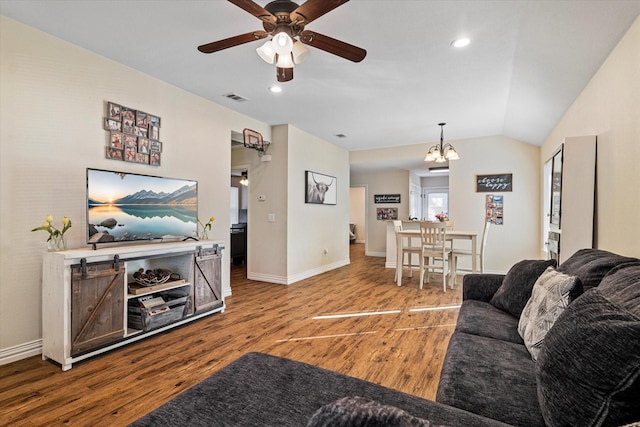 living room with hardwood / wood-style flooring, lofted ceiling, and ceiling fan with notable chandelier