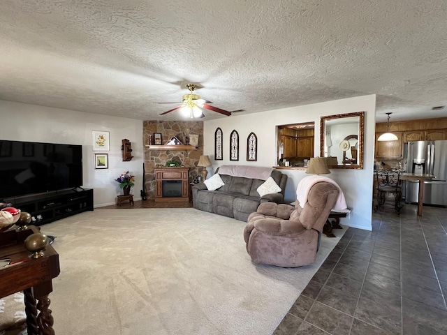 carpeted living room featuring ceiling fan, a textured ceiling, and a fireplace