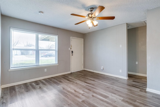 unfurnished room with ceiling fan, a textured ceiling, and wood-type flooring