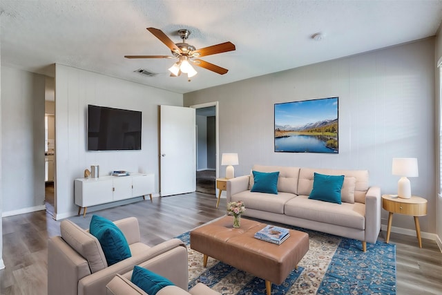 living room featuring hardwood / wood-style flooring, ceiling fan, and a textured ceiling