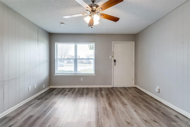 unfurnished room with wood walls, hardwood / wood-style flooring, and ceiling fan