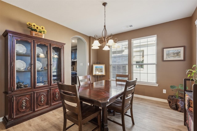 dining space featuring a notable chandelier, a healthy amount of sunlight, and light wood-type flooring