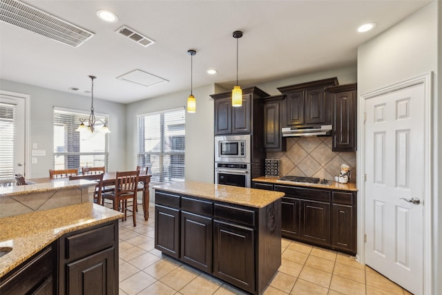 kitchen featuring a kitchen island, backsplash, hanging light fixtures, stainless steel appliances, and dark brown cabinets