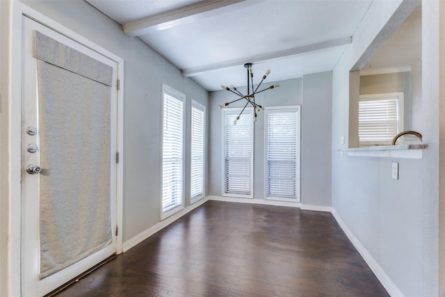 interior space with dark hardwood / wood-style floors, plenty of natural light, beam ceiling, and an inviting chandelier