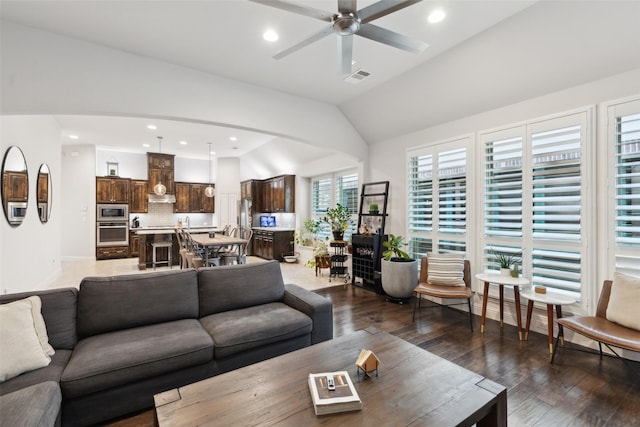 living room featuring ceiling fan, dark wood-type flooring, and vaulted ceiling