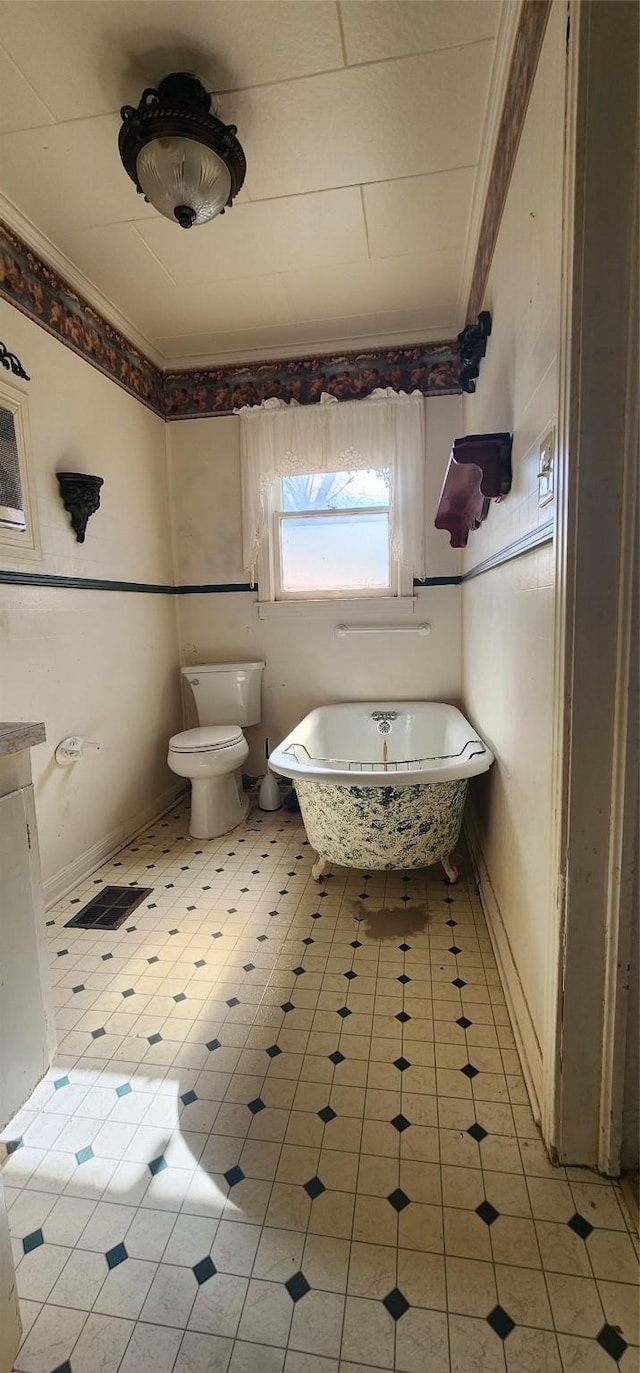 bathroom with crown molding, toilet, a bathing tub, and tile patterned floors