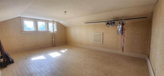 additional living space with vaulted ceiling and light hardwood / wood-style flooring