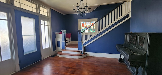 foyer featuring dark hardwood / wood-style floors, crown molding, a notable chandelier, and a healthy amount of sunlight