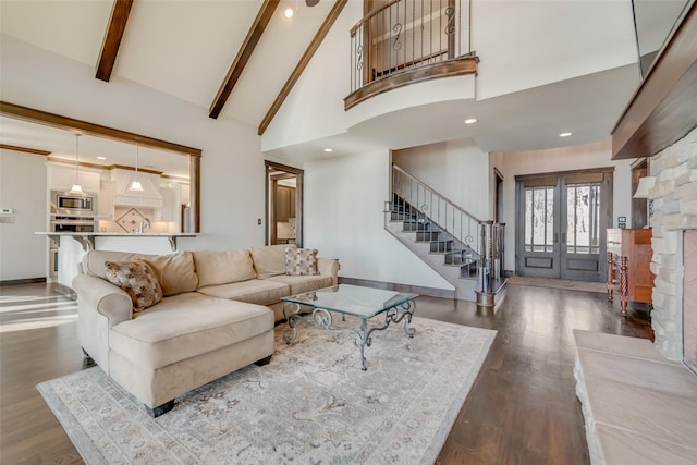 living room with beamed ceiling, a fireplace, hardwood / wood-style flooring, french doors, and high vaulted ceiling