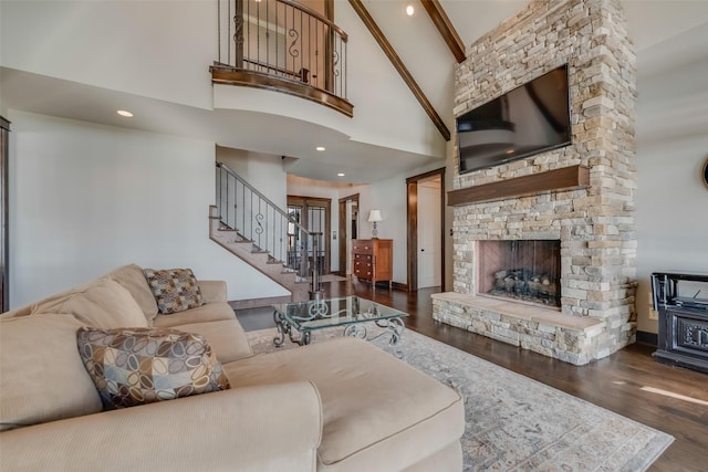 living room featuring high vaulted ceiling, dark hardwood / wood-style flooring, beam ceiling, and a stone fireplace