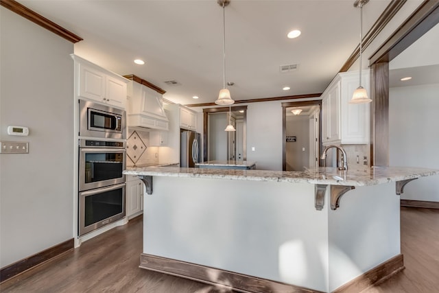 kitchen featuring light stone countertops, pendant lighting, white cabinets, appliances with stainless steel finishes, and decorative backsplash