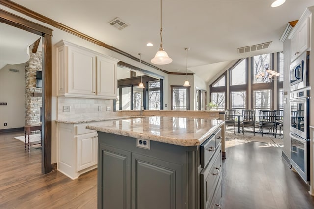 kitchen with light stone countertops, pendant lighting, white cabinets, and a kitchen island