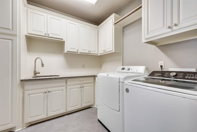 clothes washing area featuring cabinets, sink, light tile patterned floors, and washing machine and clothes dryer