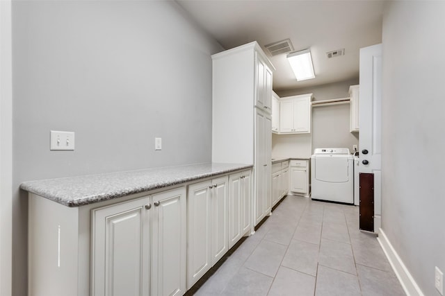 laundry room with independent washer and dryer, cabinets, and light tile patterned flooring