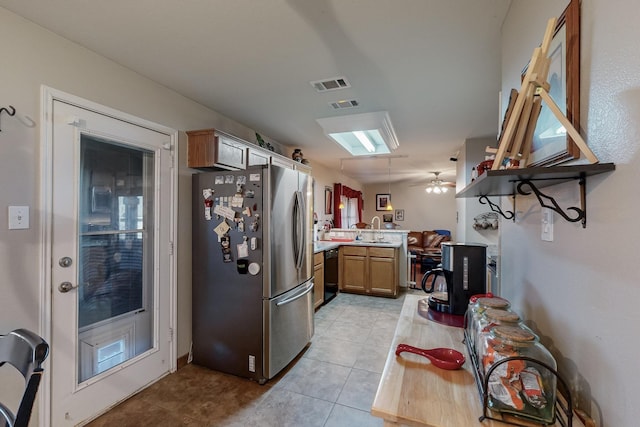 kitchen featuring sink, light tile patterned floors, stainless steel fridge, kitchen peninsula, and dishwasher