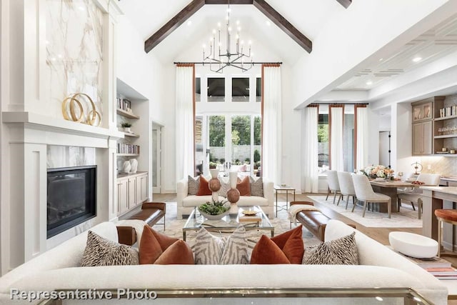 living room with beam ceiling, high vaulted ceiling, a high end fireplace, and an inviting chandelier