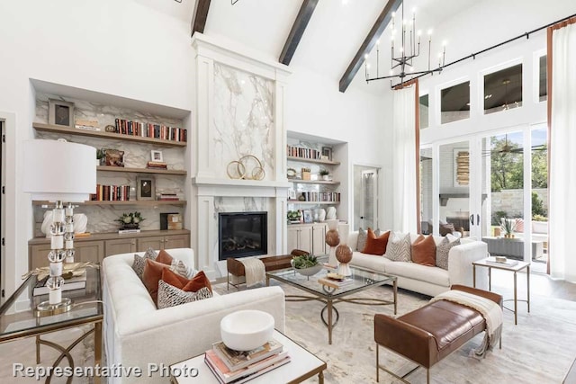 living room featuring a fireplace, a high ceiling, an inviting chandelier, beam ceiling, and built in features