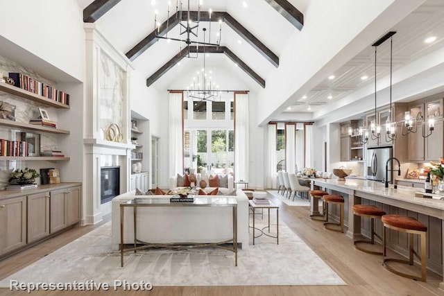 living room featuring beam ceiling, high vaulted ceiling, an inviting chandelier, and light hardwood / wood-style floors