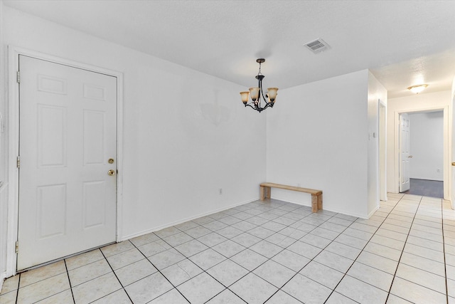 unfurnished room featuring light tile patterned flooring and an inviting chandelier