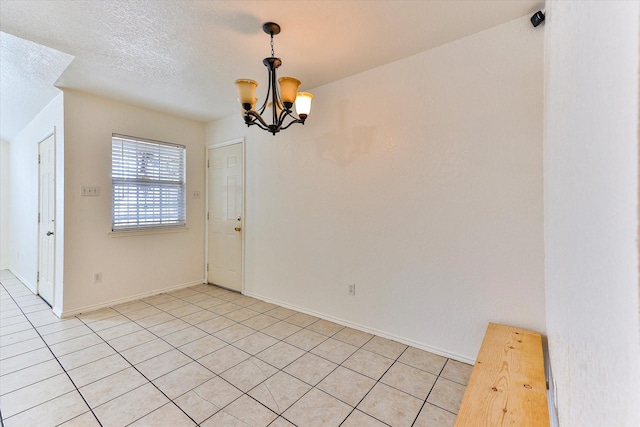 tiled spare room featuring an inviting chandelier and a textured ceiling