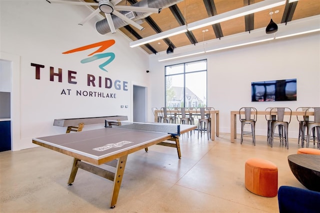 recreation room featuring concrete floors, high vaulted ceiling, beam ceiling, and ceiling fan