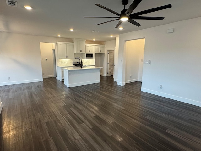 kitchen featuring dark hardwood / wood-style floors, tasteful backsplash, white cabinetry, sink, and a kitchen island with sink