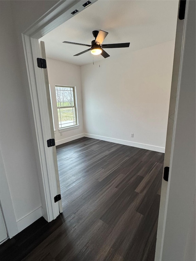 empty room with dark wood-type flooring and ceiling fan