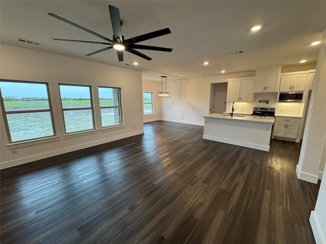 unfurnished living room featuring ceiling fan, a water view, sink, and dark hardwood / wood-style flooring