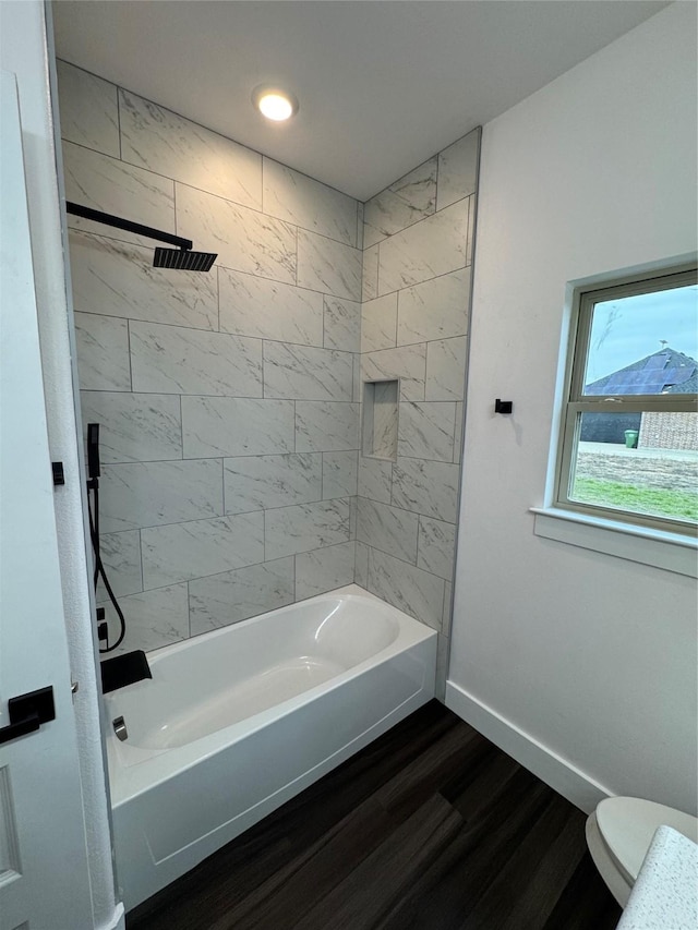 bathroom featuring tiled shower / bath combo, toilet, and hardwood / wood-style flooring