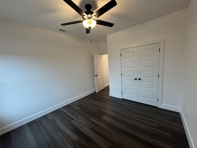 unfurnished bedroom with dark wood-type flooring, a closet, and ceiling fan