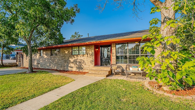 ranch-style home featuring a front lawn and a patio