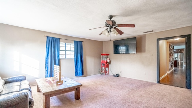 carpeted living room with ceiling fan and a textured ceiling