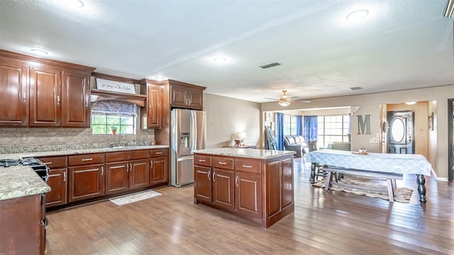 kitchen featuring a center island, stainless steel refrigerator with ice dispenser, sink, backsplash, and light hardwood / wood-style flooring