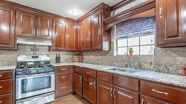 kitchen featuring gas stove, decorative backsplash, sink, light hardwood / wood-style floors, and light stone counters