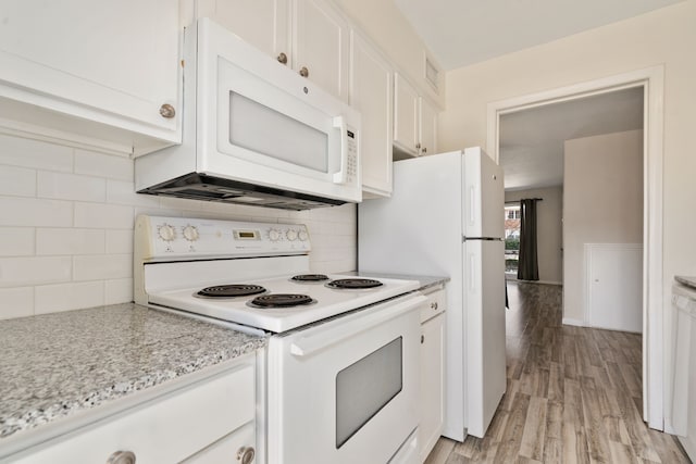 kitchen with white appliances, white cabinets, tasteful backsplash, light wood-type flooring, and light stone counters