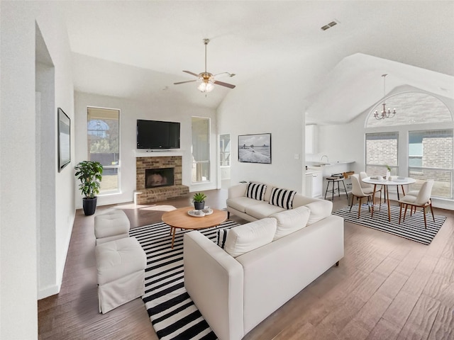 living room with plenty of natural light, wood-type flooring, lofted ceiling, and a stone fireplace