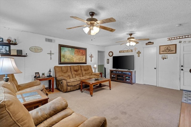 carpeted living room featuring ceiling fan and a textured ceiling